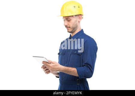 Ritratto orizzontale medio di un bel giovane adulto di successo, ingegnere di costruzione caucasico che indossa uniforme utilizzando una tavoletta digitale, sfondo bianco Foto Stock