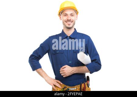 Orizzontale medio ritratto di sicuro bel giovane adulto ingegnere caucasico indossando uniforme blu holding piano di costruzione, sfondo bianco Foto Stock