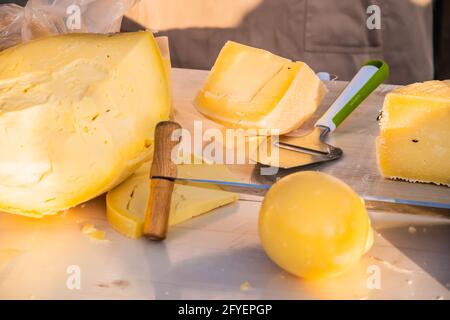 Formaggio artigianale in un mercato di strada. Caseificio tagliando il formaggio nel suo laboratorio. Festa del cibo nel parco cittadino. Street fast food. Foto Stock