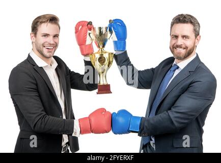 due uomini d'affari felici in guanti di boxe tengono coppa campione dopo la battaglia per la leadership, campionato. Foto Stock