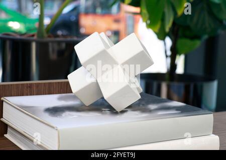 una forma poligonale in ceramica bianca messa sul libro in soggiorno per decorazione Foto Stock