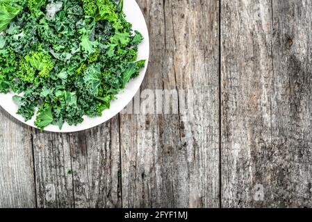 Preparazione di patatine di verdure verdi da foglie di kale affettate su piastra, dall'alto, spazio di copia Foto Stock