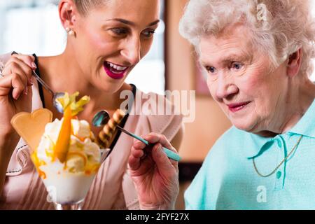 Donna Senior e nipote divertirsi a mangiare il gelato Gelato in cafe Foto Stock