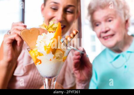 Donna Senior e nipote divertirsi a mangiare il gelato Gelato in cafe Foto Stock