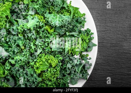 Verdure verdi, foglie di kale, vista dall'alto sul piatto, concetto di alimentazione sana Foto Stock