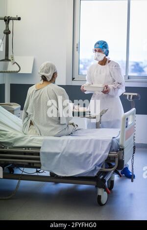 Infermiera nella stanza di un paziente anziano, unità di ricovero Covid della CHU de Limoges. Foto Stock