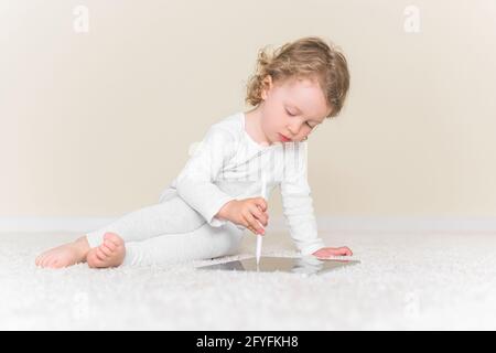 La bambina disegna o gioca sul computer tablet. Foto Stock