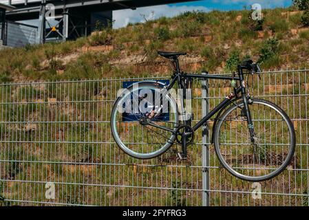 Una bicicletta pende su una recinzione Foto Stock