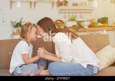 Il rapporto di fiducia di mamma e figlia. Conversazione di una donna con una bambina a casa sul divano in cucina. Migliori amici buon Moth felice Foto Stock