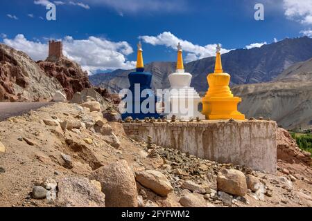 Tre stupa religiosi buddisti colorati a Leh, Ladakh, Jammu e Kashmir, India. Simboli religiosi nel paesaggio, con montagna e strada himalaya. Foto Stock