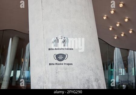 Amburgo, Germania. 28 maggio 2021. Un avviso con l'iscrizione ''si prega di mantenere la distanza. Si prega di indossare una maschera'' scritta su una colonna nella piazza Elbphilharmonie. L'Elbphilharmonie Plaza è stato riaperto dopo una pausa a causa della corona. Credit: Georg Wendt/dpa/Alamy Live News Foto Stock