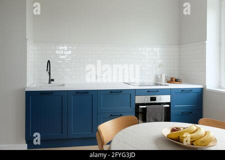 Cucina semplice in stile scandinavo senza armadi superiori, piccola cucina nordica con armadi blu. Interni dal design moderno. Foto Stock