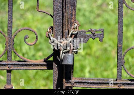 Il cancello arrugginito è bloccato con un lucchetto con una catena. Foto Stock