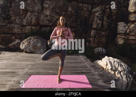 Donna caucasica tranquilla che pratica yoga in piedi su una gamba dentro ambiente rurale di montagna Foto Stock