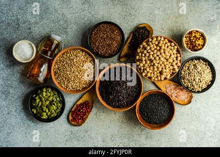 Ciotole di semi di zucca, semi di girasole, semi di lino, ceci, semi di sesamo, peperoncini, olio, pepe, riso e sale Foto Stock