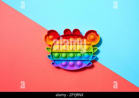 I giocattoli alla moda pop it in forma di granchio su colorati sfondo rosso e blu. Vista dall'alto - disposizione piatta Foto Stock