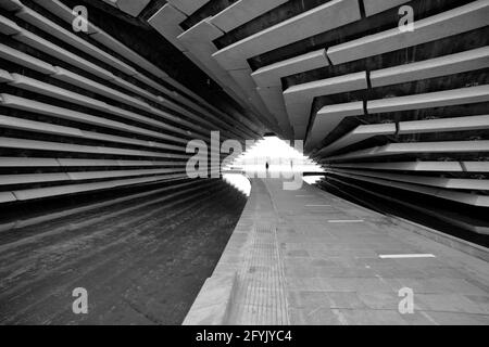 Un'immagine monocromatica di una figura sola sotto il V&A Museum Dundee guardando verso la passeggiata lungo il fiume Tay. Foto Stock