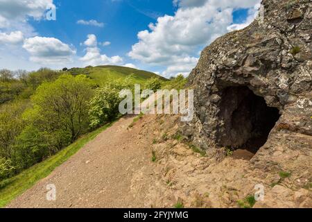 L'ingresso alla grotta di Clutter's Cave nelle colline di Malvern con il campo britannico sullo sfondo, Worcestershire, Inghilterra Foto Stock