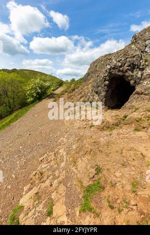 L'ingresso alla grotta di Clutter's Cave nelle colline di Malvern con il campo britannico sullo sfondo, Worcestershire, Inghilterra Foto Stock