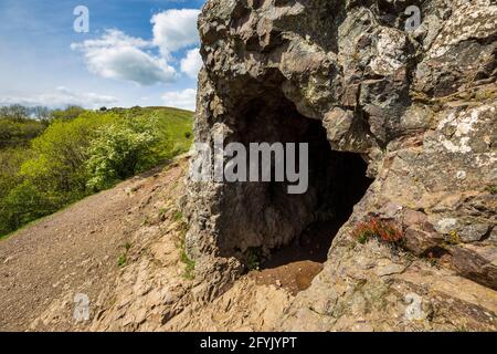 L'ingresso alla grotta di Clutter's Cave nelle colline di Malvern con il campo britannico sullo sfondo, Worcestershire, Inghilterra Foto Stock