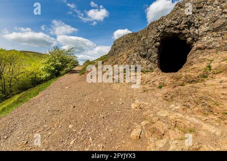 L'ingresso alla grotta di Clutter's Cave nelle colline di Malvern con il campo britannico sullo sfondo, Worcestershire, Inghilterra Foto Stock