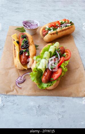 Deliziosi hot dog appena cotti con salsicce, verdure, formaggio e salsa su A. Foto Stock