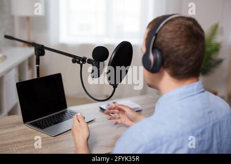 concetto di radio, podcast e blog audio - vista posteriore di blogger maschile o giornalista che registra podcast audio a casa Foto Stock