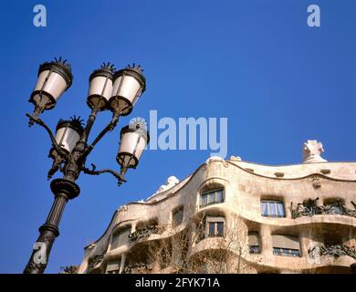 BARCELLONA, SPAGNA - 19 APRILE 2019: La casa di Case Mila con vecchia lanterna di fronte. Questa casa è stata progettata da Antoni Gaudi. Questa casa è un UNESCO Worl Foto Stock