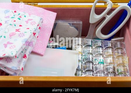 Selezione di accessori per cucire in una scatola da cucire, con tessuto rosa Foto Stock