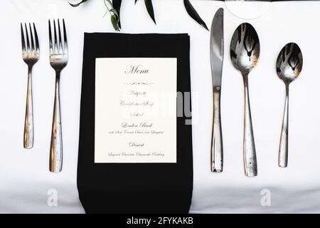 Ambiente personale per cene sociali in bianco e nero, forchette, cucchiai, coltello e menu Foto Stock