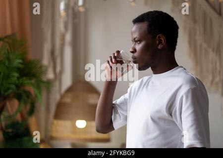 Atleta africano a casa con un bicchiere d'acqua dopo l'allenamento sportivo. Foto Stock