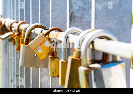 Lucchetto d'oro con un paio di cuori strondati. Un paio di vecchie e arrugginite serrature accoppiate tra molti altri come un simbolo di amore per sempre. Antico mestato di nozze Foto Stock