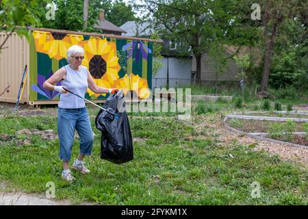 Detroit, Micigan -Susan Newell, 72 anni, raccoglie la lettiera in un giardino durante una pulizia annuale in tutta la città chiamata Motor City Makeover. Foto Stock
