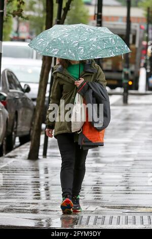 Londra, Regno Unito. 24 maggio 2021. Una donna si rifuga dalla pioggia sotto un ombrello a Londra. Credit: Dinendra Haria/SOPA Images/ZUMA Wire/Alamy Live News Foto Stock