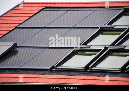 moduli solari per la produzione di elettricità dalla luce solare integrati nel tetto di una casa indipendente di fronte al cielo Foto Stock