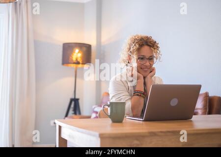 Head shot piacevole felice giovane donna freelance che lavora sul computer a casa. Attraente donna d'affari che studia online, utilizzando software per computer portatili, web surf Foto Stock