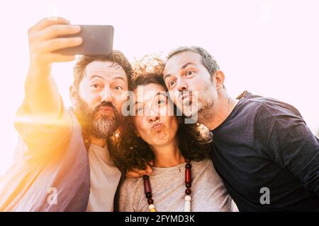 Gruppo di tre giovani amici adulti scatta foto selfie facendo espressione piacevole - la gente di mezza età usa il cellulare per prendere una foto - concetto di amicizia Foto Stock