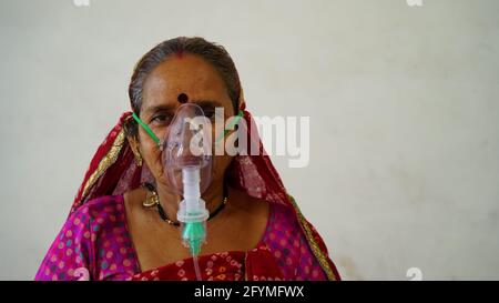 Maggio 2021- Jaipur, India. Vecchia donna indiana infettata con la malattia di Covid 19. Maschera per l'inalazione di ossigeno con flusso di ossigeno liquido. Foto Stock