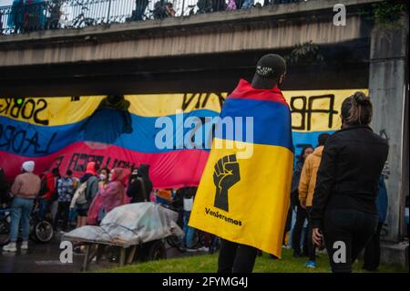 Un manifestante porta una bandiera colombiana con un pugno rischiato mentre migliaia di persone si sono riunite per protestare contro il presidente della Colombia Ivan Duque Maraquez e contro i casi di disordini e brutalità della polizia che avevano lasciato almeno 45 morti durante il primo mese di manifestazioni, a Bogotà, Colombia, il 28 maggio; 2021. Foto Stock