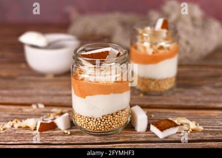 Colazione a strati o dessert con grani di quinoa soffiati, yogurt e fiocchi di cocco e pezzi in vetro Foto Stock