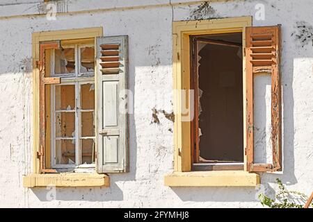 Due vecchie finestre danneggiate con persiane di vecchio edificio abbandonato Foto Stock