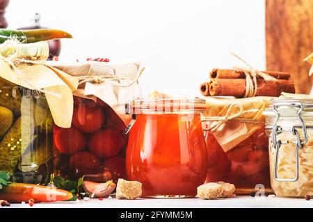 Cibo vegetariano fermentato, sottaceto, marinato conservato. Verdure biologiche estive e frutta in vasi con spezie ed erbe sulla cucina bianca Foto Stock