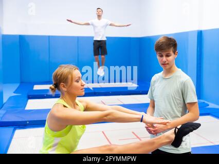 Allenatore femminile esperto che tiene l'addestramento con l'adolescente nella stanza del trampolino, spiegando i trucchi di salto di base Foto Stock