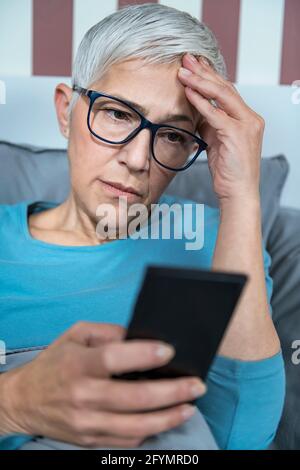 Donna che usa lo smartphone a letto Foto Stock