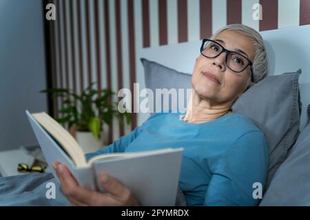Donna lettura a letto Foto Stock