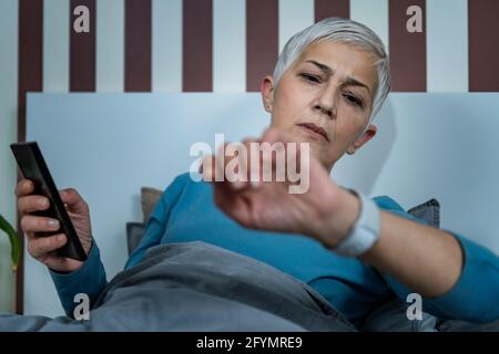 Donna anziana che controlla il tracker del sonno dell'orologio intelligente Foto Stock