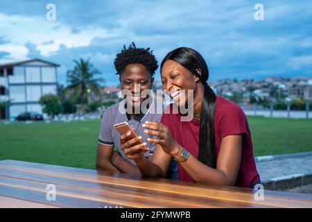 Ridendo amici che guardano uno smartphone Foto Stock