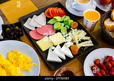 Colazione Halal con diversi tipi di formaggio, fette di salsiccia, uova, verdure fresche, olive e pane tradizionalmente serviti con tè in h turca Foto Stock