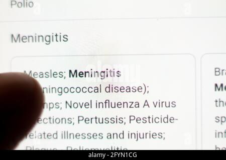 Meningitis News sul telefono cellulare.cellulare in mani. Fuoco selettivo e aberrazione cromatica effetti. Foto Stock