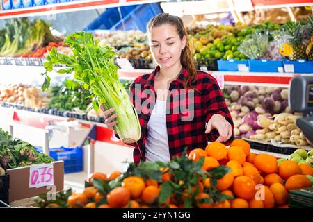 Un'assistente amichevole del negozio femminile sta aiutando ad acquistare arance al supermercato Foto Stock